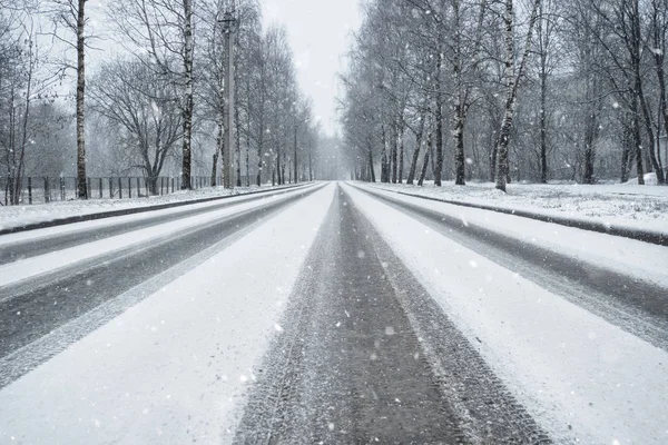 Зимняя дорога в снегопад. Колесные дорожки на снежной дороге — стоковое фото