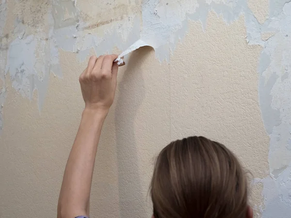 Mão removendo papel de parede velho durante o reparo . — Fotografia de Stock