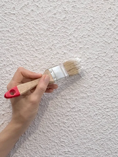Mano sostiene pincel de pintura y pintar una pared — Foto de Stock