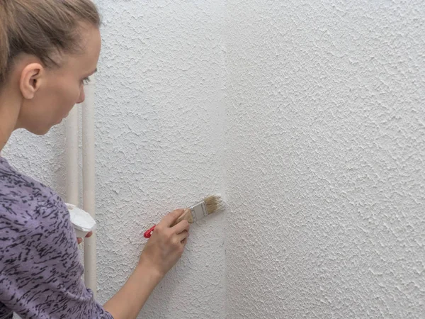 Mujer pintando la pared. Restauración de las paredes pintadas de blanco — Foto de Stock