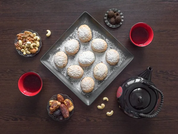Χειροποίητα γλυκά του Ραμαζανιού σερβίρονται με τσάι στο σκούρο ξύλινο τραπέζι. Αιγυπτιακά cookies "Kahk El Eid" - cookies του El Fitr Islamic Feast. Άνω όψη — Φωτογραφία Αρχείου
