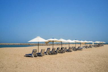 Beach umbrellas are in one line. Ras Al Khaima on the Persian Gulf