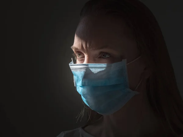 En kvinna som tar på sig en medicinsk engångsmask för att undvika smittsamma virus — Stockfoto