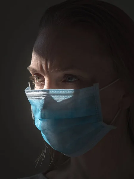 Karanlık bir geçmişi olan bir kadın virüslü enfeksiyonları önlemek için tek kullanımlık bir maske takıyor. — Stok fotoğraf
