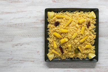 Biryani ve bebek mısır. Baharatlı bebek mısır pilavı ahşap masada.
