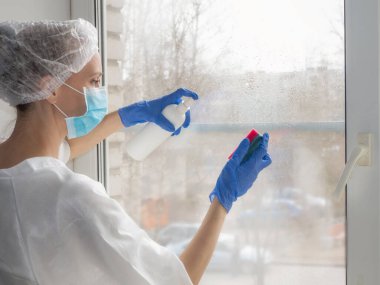 Coronavirus dezenfeksiyonu. Pencerelerde dezenfeksiyon yapan insanlar. Lastik eldivenli doktor pencereleri dezenfektan ve süngerle dezenfekte eder.