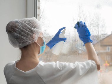 Coronavirus dezenfeksiyonu. Pencerelerde dezenfeksiyon yapan insanlar. Lastik eldivenli doktor pencereleri dezenfektan ve süngerle dezenfekte eder.