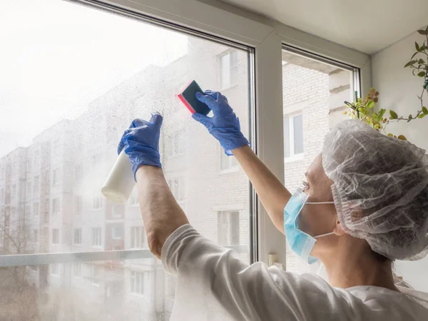 Desinfección por Coronavirus. Gente haciendo desinfección en ventanas. Doctor en guantes de goma desinfecta ventanas con desinfectante y esponjas — Foto de Stock