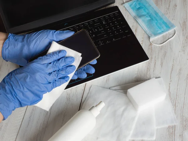 Las manos en guantes azules limpian la pantalla del teléfono inteligente con tela desinfectante de bacterias y virus — Foto de Stock