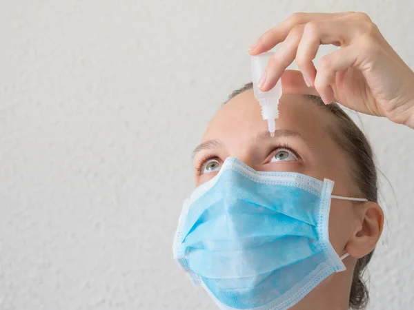 Mujer con máscara médica usando gotas para los ojos. Prevención de infecciones virales —  Fotos de Stock