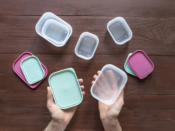 Plastic containers for transportation and storage food products laid out on a wooden table. Top view