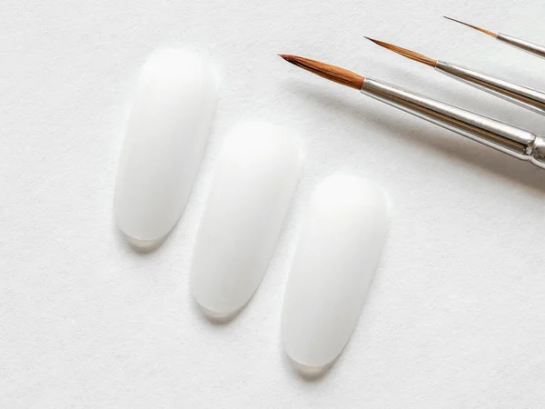 Kreatywna koncepcja manicure. Czyste końcówki i pędzle malarskie różnej wielkości do manicure na białym tle — Zdjęcie stockowe