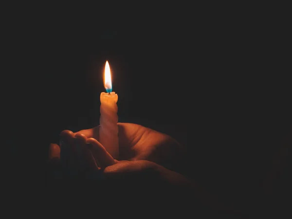 Горящая свеча в мужской руке на черном фоне — стоковое фото