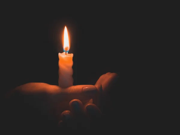 Queimando vela na mão masculina em um fundo preto — Fotografia de Stock