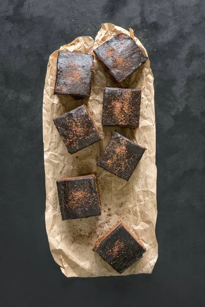 Свежеиспеченные классические пирожные на пергаменте выложены на черной поверхности — стоковое фото