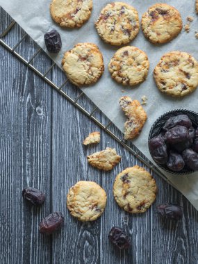 Koyu bir ahşap yüzeyde, üzerinde hurma bulunan karidesler serilmiştir.