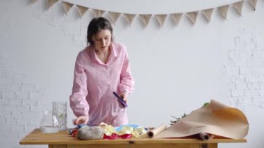 Genç bir çiçekçi bir buket oluşturmak için bir iş istasyonu hazırlar