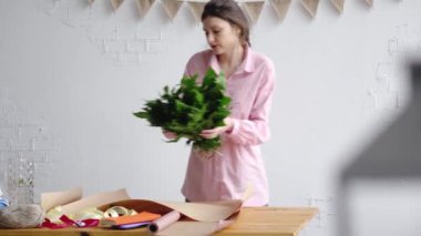 Çiçekçi yeşillik buketi oluşturmak için kağıt üzerinde koyar. Çiçek iş