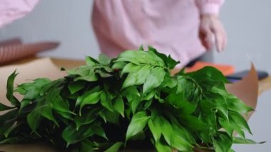 Çiçekçi güzel bir buket oluşturmak için Araçlar hazırlar. Yeşil arka planı.