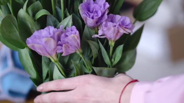 Mains féminines avec de belles fleurs - eustomes de jaune et de violet à bout portant — Video