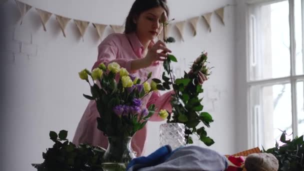 Florista coloca rosa em um vaso de vidro com água. Tiro de mão em tempo real . — Vídeo de Stock