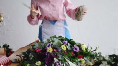 Çiçekçi önden görünümü bir iş parçacığı bir buket düzenlemek için makas ile keser.