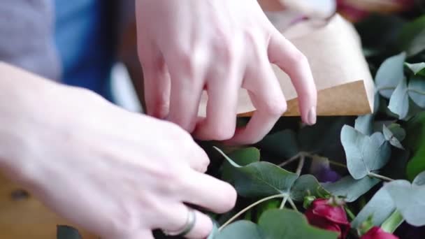 Florista usando grampeador para anexar um papel artesanal. Vista de perto de organizar buquê — Vídeo de Stock