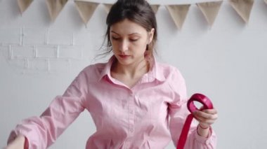 Profesyonel kadın çiçekçi kırmızı kurdeleyi açar, buketi paketlemek için makasla keser.