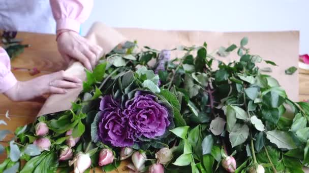 Профессиональный флорист, заворачивающий цветы в бумагу в цветочном магазине — стоковое видео