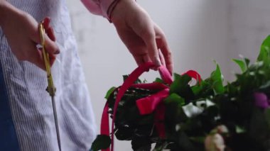 Çiçekçi kırmızı kurdele buket üzerinde makas ile keser
