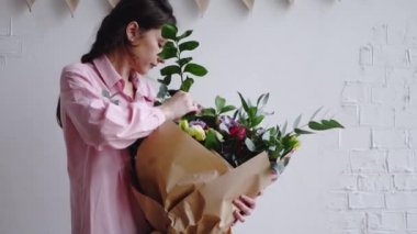 Çiçekçi yeşillik bir dalı büyük bir modern buket ekler.