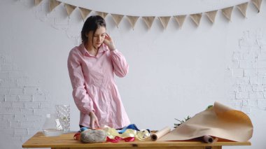 Genç bir çiçekçi bir buket oluşturmak için bir iş istasyonu hazırlar