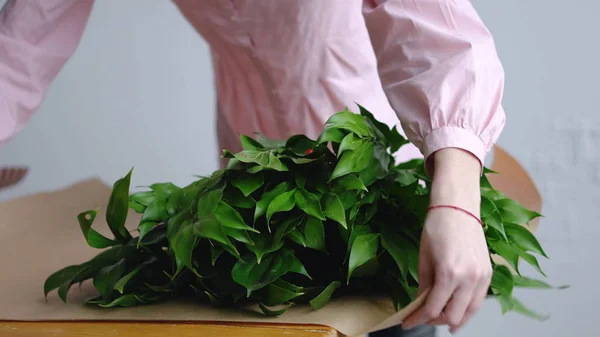 Kvinnliga florist sorterar ut gröna för en bukett på kraftpapper — Stockfoto