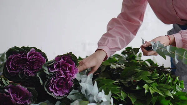 Florista profissional arranja flores para criar um buquê — Fotografia de Stock