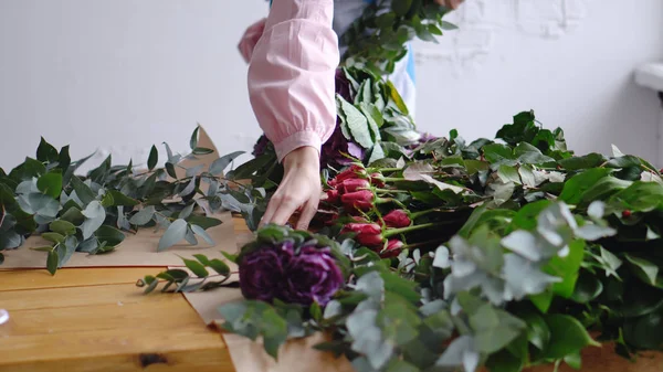 Uma florista mulher está colocando flores em seu local de trabalho — Fotografia de Stock