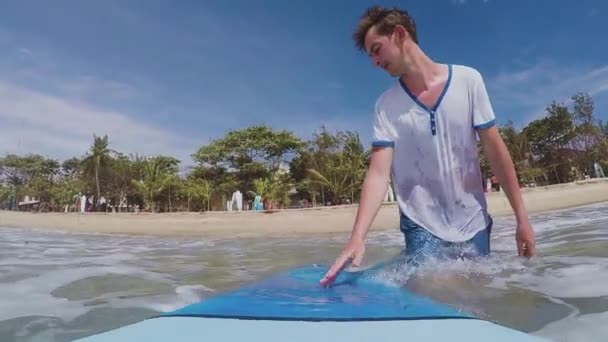 Повільний рух: молодий серфер йде в океан з дошкою для серфінгу — стокове відео