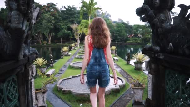 Mladá dívka sestupuje po schodech v starověké krásného parku v Bali — Stock video