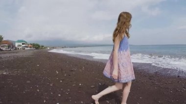 Güzel kız siyah volkanik kum plajda etrafına bakıyor