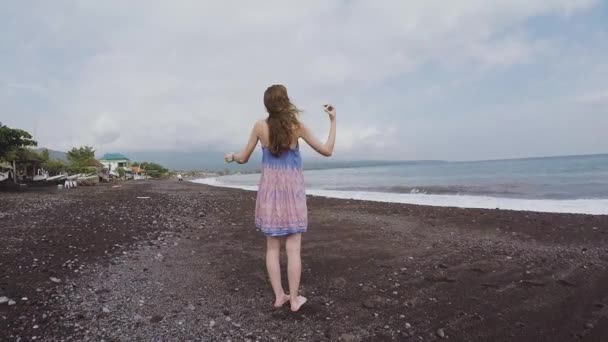 Bali volkanik kum dışarı siyah bir plaj boyunca uzun boylu kız yürüyor — Stok video
