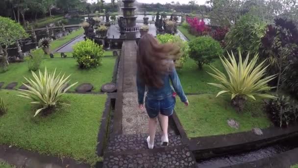 Jonge toeristische meisje gaat naar een prachtige fontein in Balinese Hindoe water paleis Tirta Gangga — Stockvideo