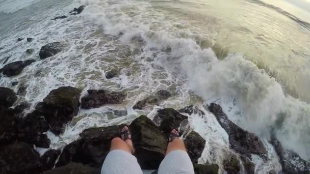 FPV: benen tegen de achtergrond van grote golven die breken tegen de rotsen in super slow motion — Stockvideo