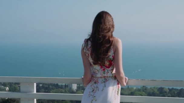 Hermosa chica caucásica en una terraza sobre la ciudad contra el mar — Vídeo de stock
