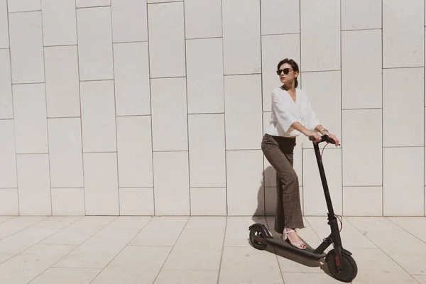 Bir kadın parkta elektrikli scooter kullanır. Trafik sıkışıklığı olmadan şehir etrafında hızlı hareket için yeni gadget