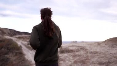 Kız koşucu denizin yukarısındaki yüksek uçurumda antrenman yapıyor. Okyanus kenarında sabah koşusu. Sweatshirt takibi için kardiyo egzersizi