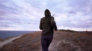 Bir kadın alacakaranlıkta uçurumda koşuyor. Açık hava koşu antrenmanı sırasında eşofmanlı bir kadın.