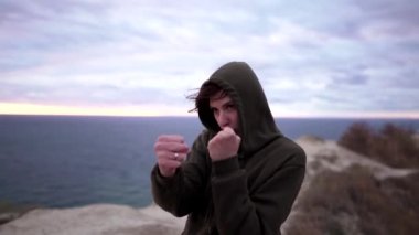 Kadın kickboksör eğitimi ve açık havada boks. Eşofmanlı genç kendine güvenen sporcu kadın hava saldırısı düzenliyor.