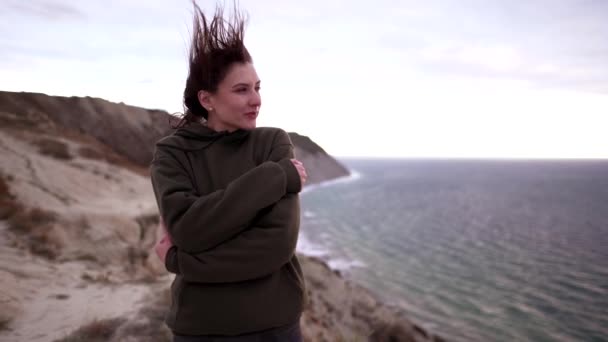 Hermosa deportista en un viento huracán al aire libre. Retrato de una mujer delgada en ropa deportiva y una sudadera. El concepto de fitness, éxito y estilo de vida saludable — Vídeos de Stock