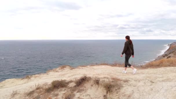 Un atleta feliz y alegre gira y siente la libertad al borde de un acantilado. Estilo de vida deportivo — Vídeo de stock