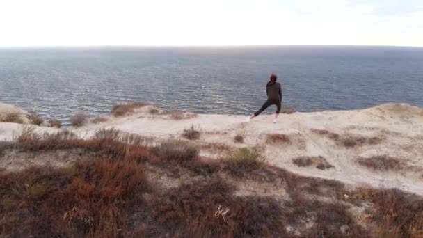 Drone vista en el entrenamiento, mujer atractiva en una sudadera. pose de estiramiento al aire libre antes del amanecer — Vídeo de stock