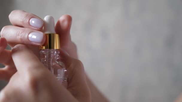 Il palmo della mano femminile apre un flacone con una pipetta. Siero viso naturale. Gocce di liquido essenziale cadono da un contagocce. Aromaterapia, essenza e relax — Video Stock